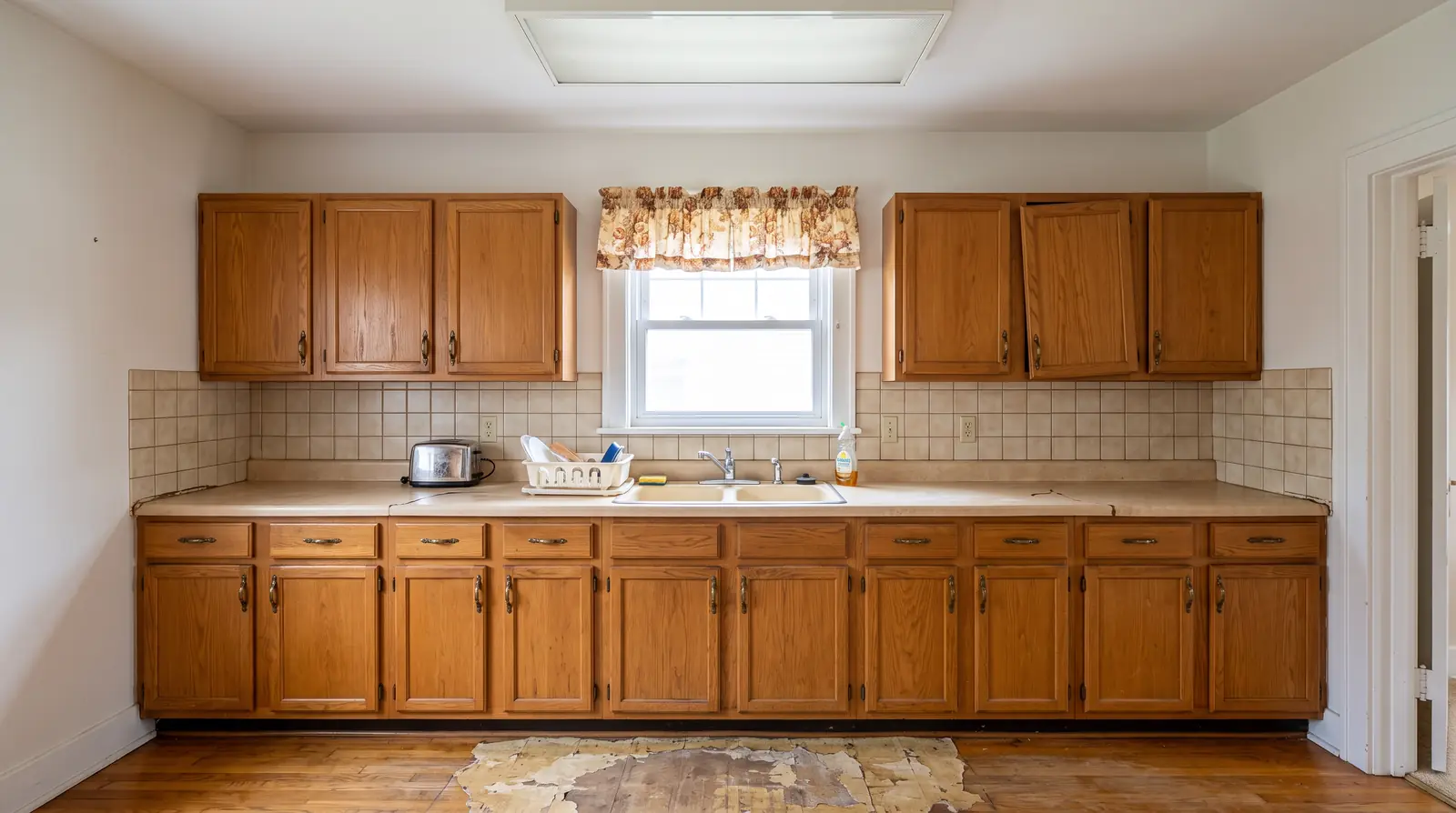 Before: a tired 1978 kitchen with honey oak cabinets, almond laminate counters and a fluorescent ceiling box